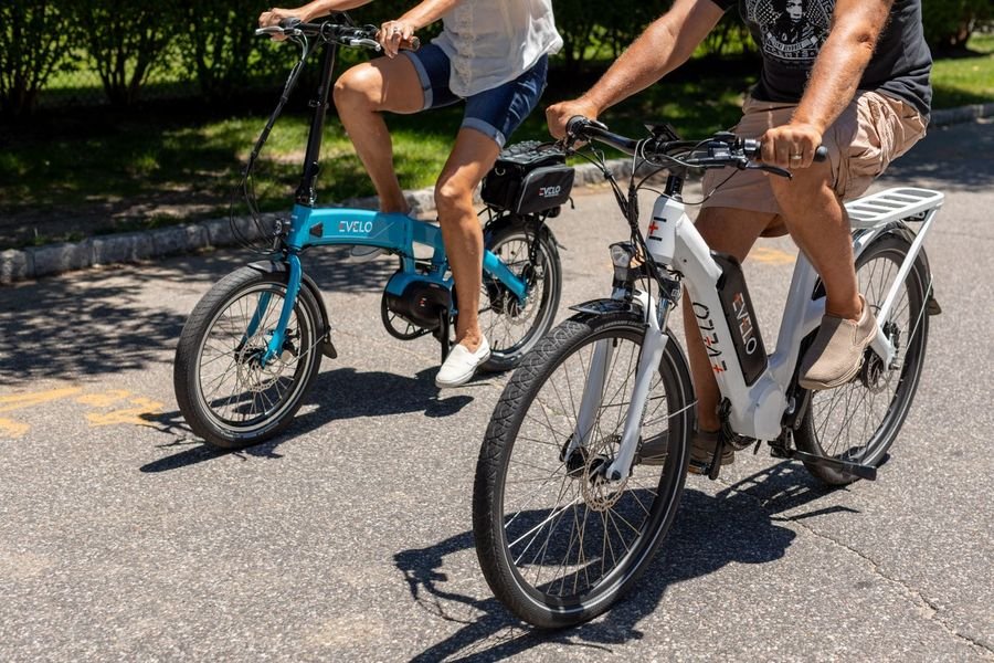 Two people riding electric bikes through a park